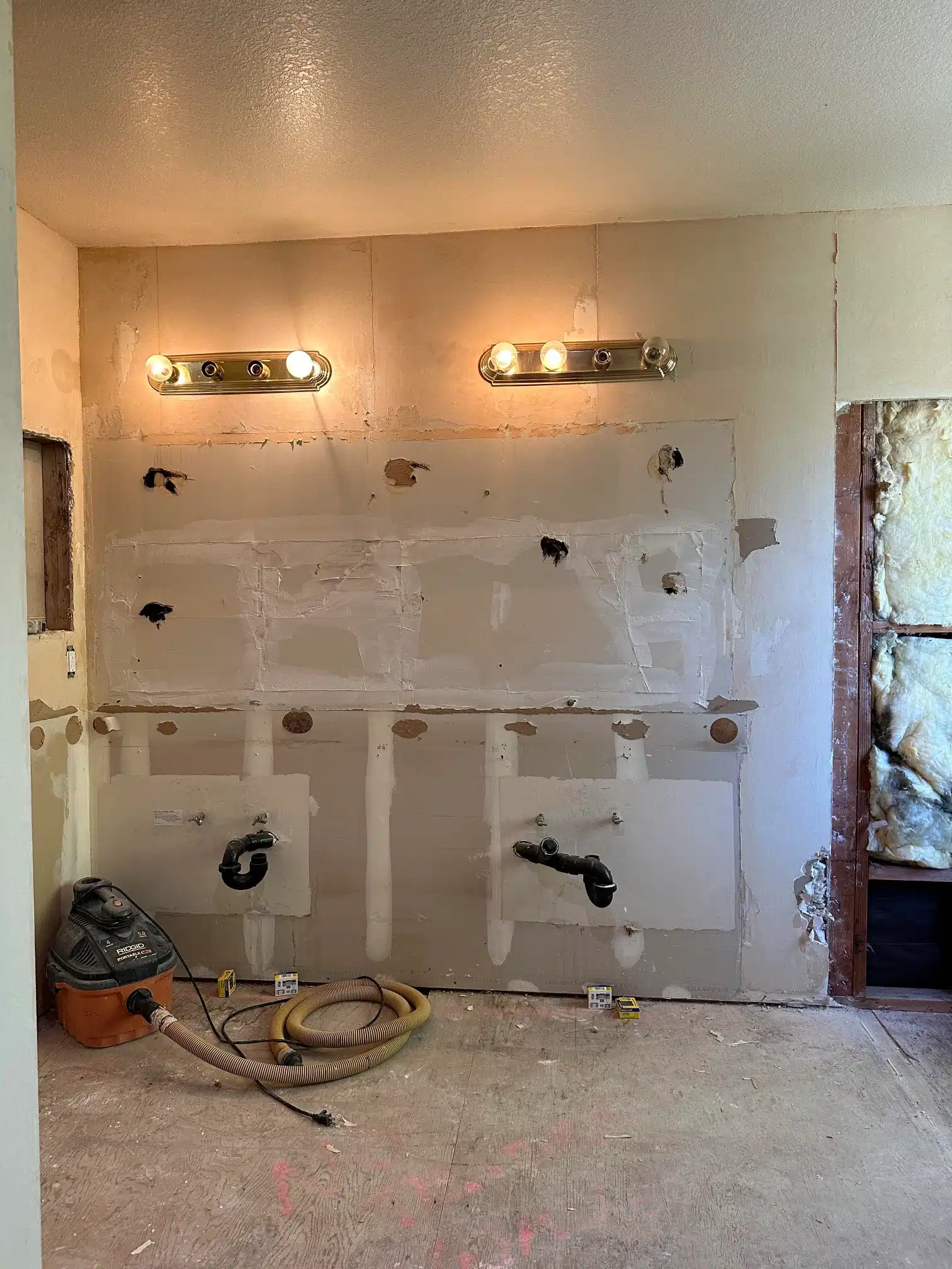 Plumbing rough-in set out across the open bathroom wall