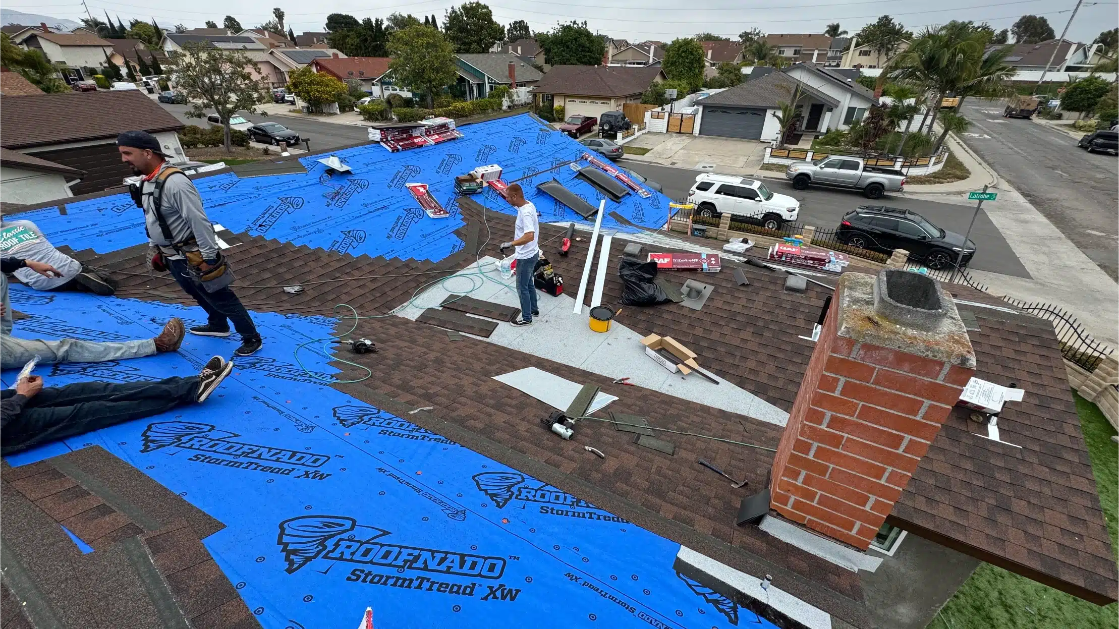 The house stripped to the deck during the re-roof, with tarps and materials staged