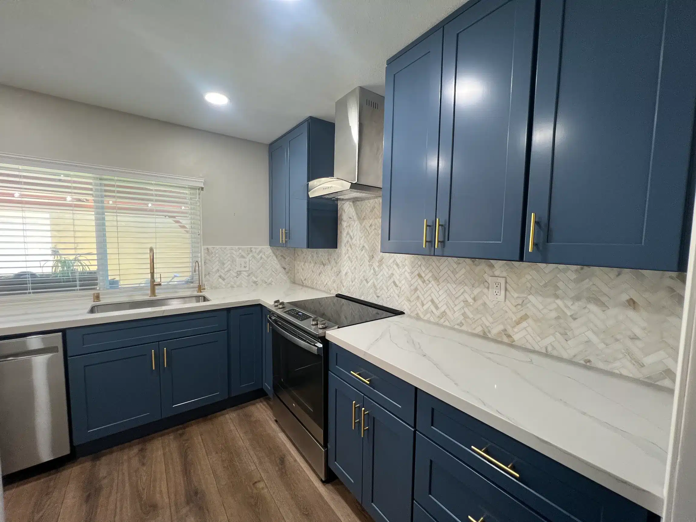 Kitchen remodel in San Diego with navy shaker cabinetry, stone counters and a marble-veined backsplash