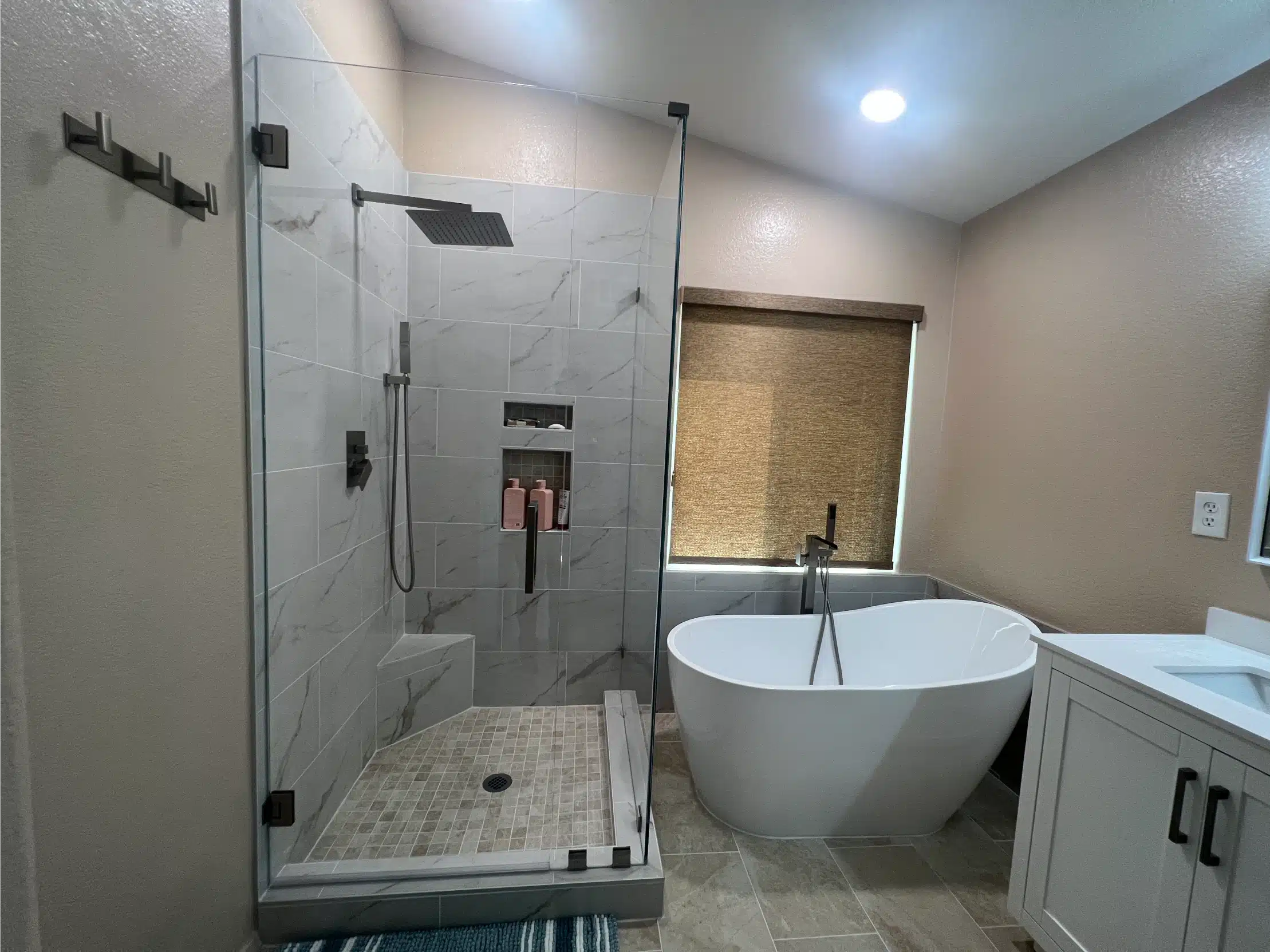 Shower, tub and vanity seen together across the finished room