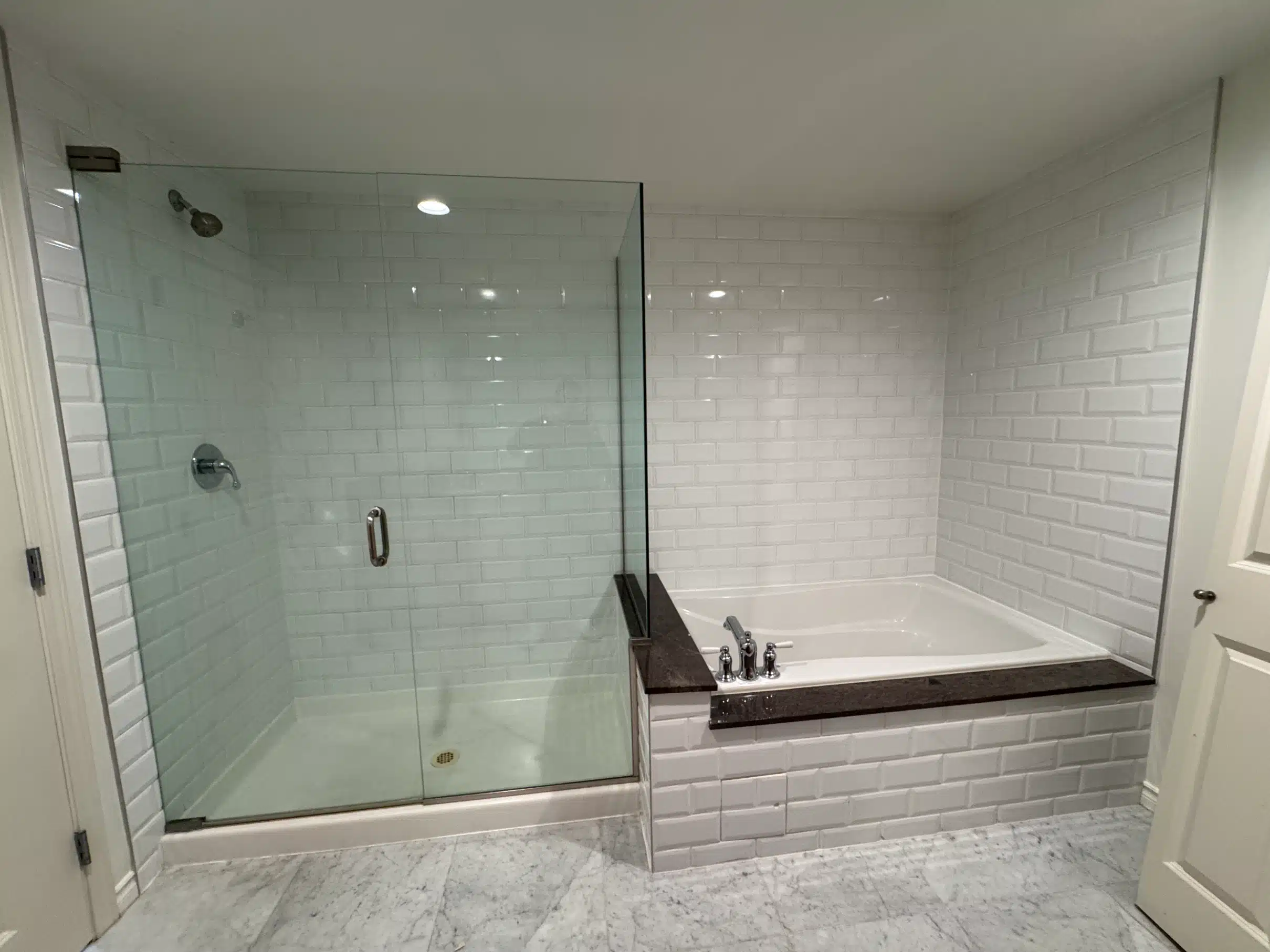 Shower finished in white tile with a built-in bench and frameless glass