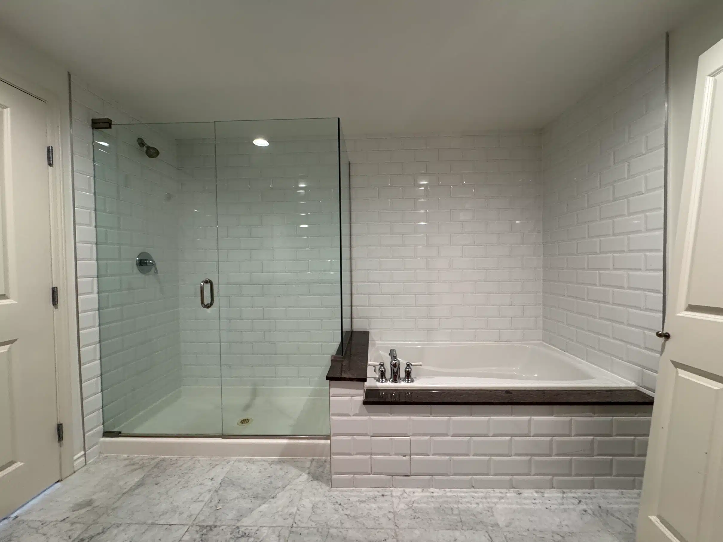 White tile shower enclosure with a built-in bench, seen from the opposite side
