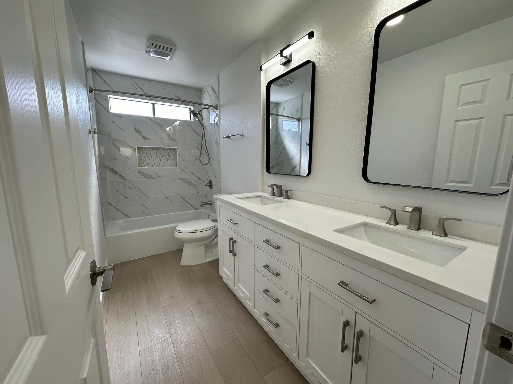 The rebuilt bathroom with a double vanity and marble-look tile