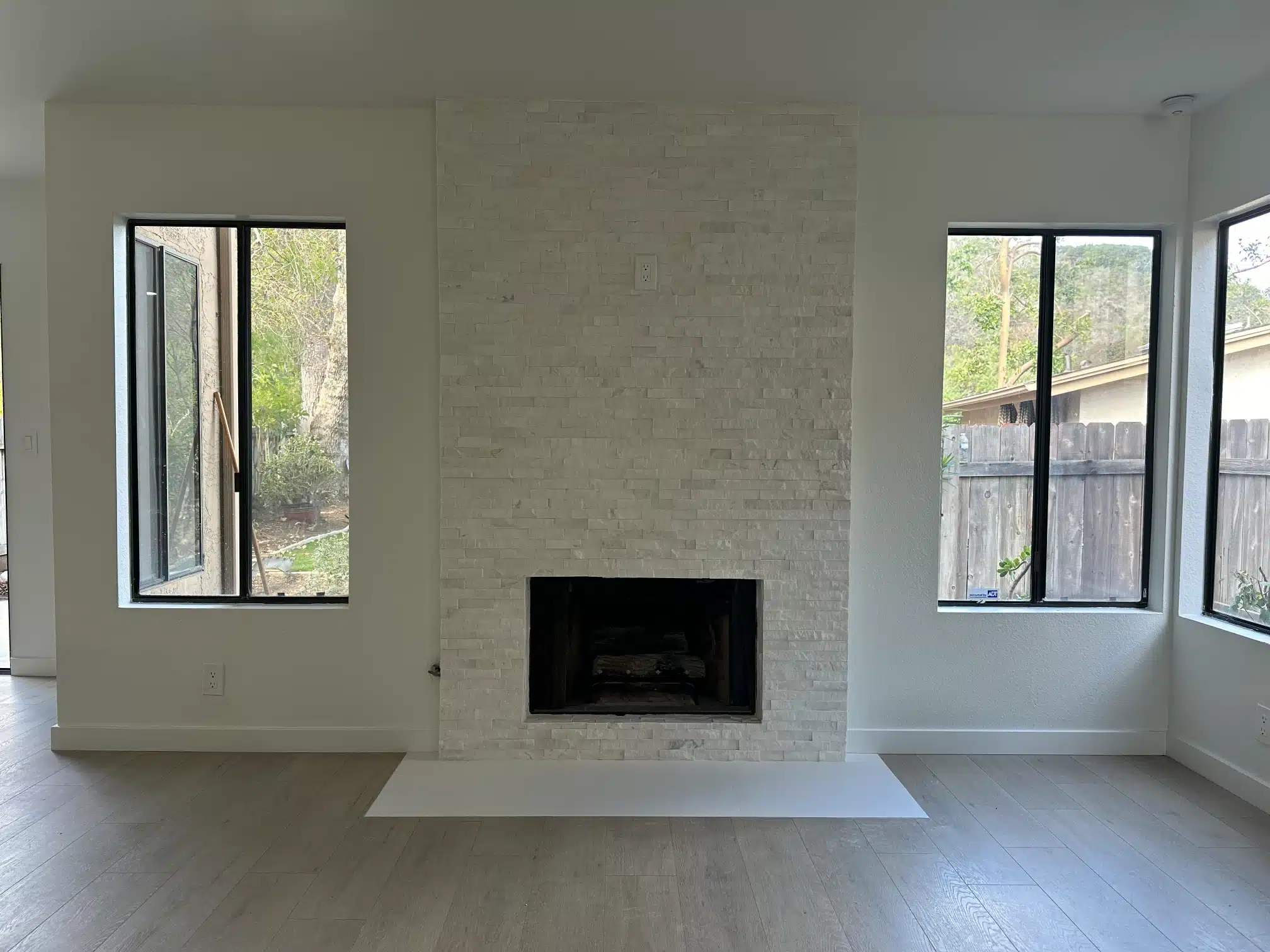 Remodelled living room in San Carlos with a white stone fireplace flanked by new windows