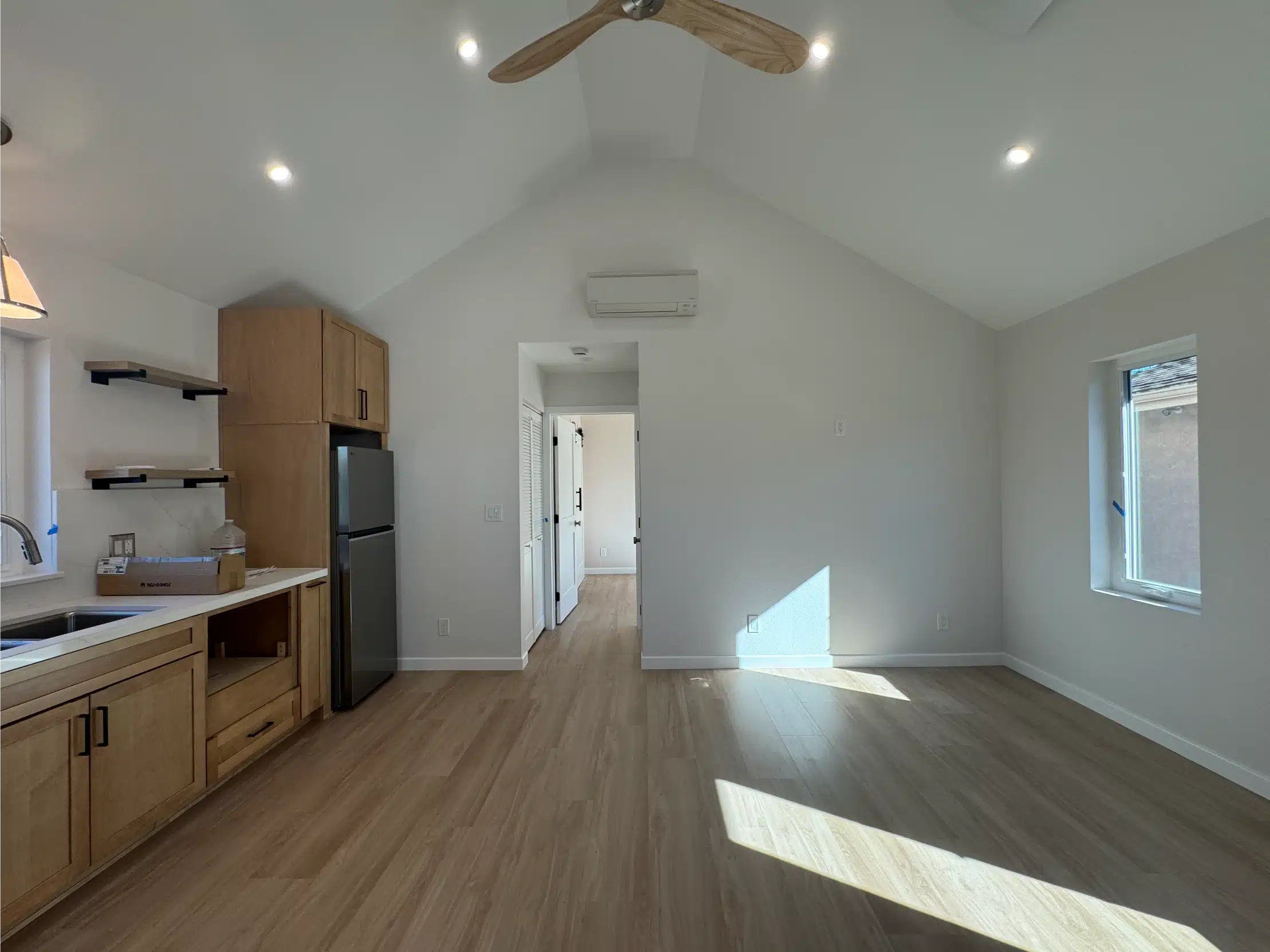 Finished ADU interior with a full kitchen, vaulted ceiling and plank flooring