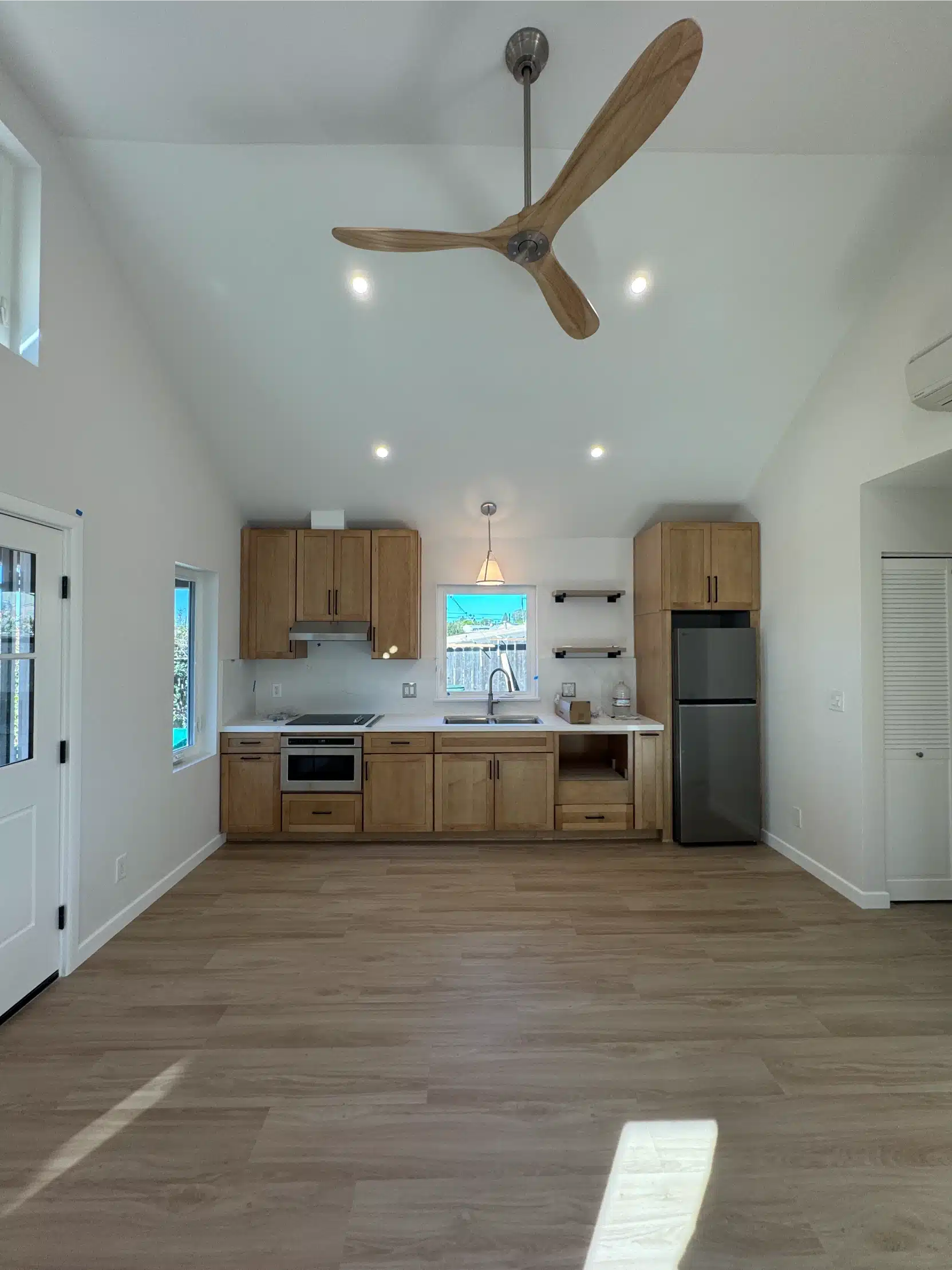 The ADU kitchen with oak cabinetry, integrated appliances and open shelving
