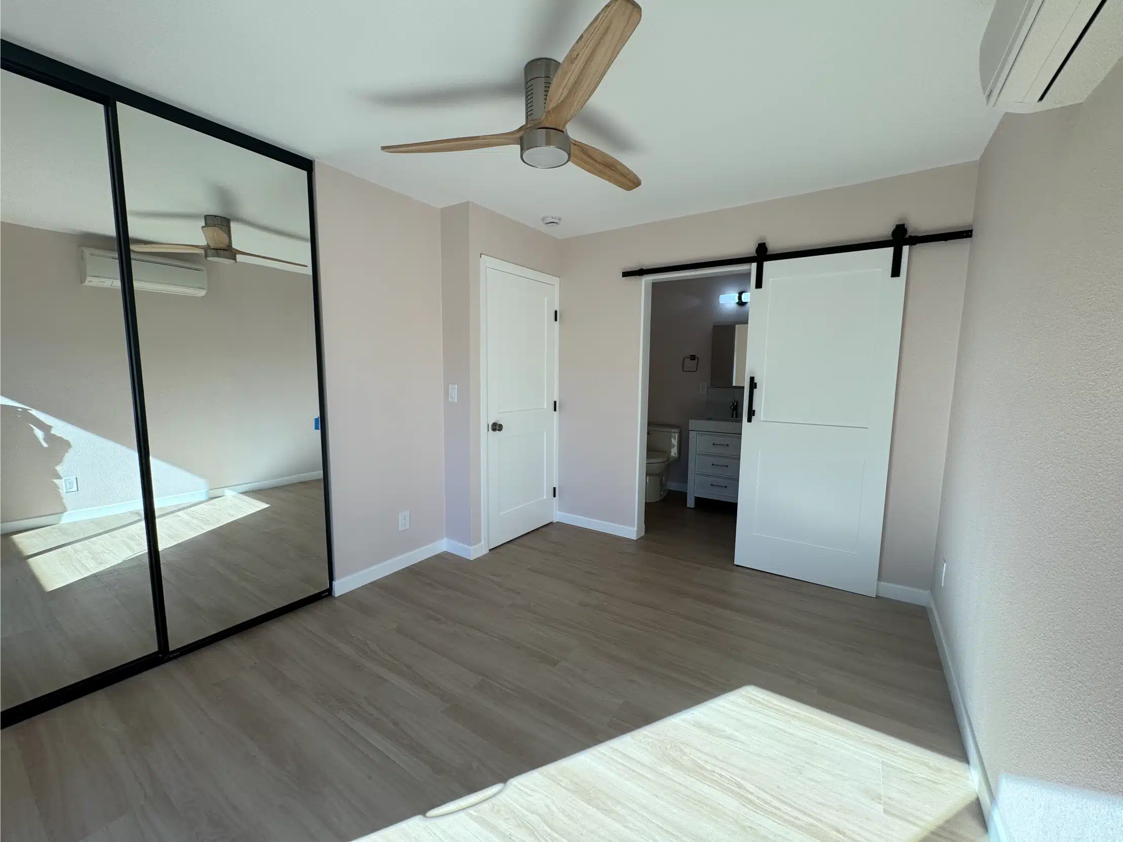ADU bedroom area with a sliding barn door and mirrored closet