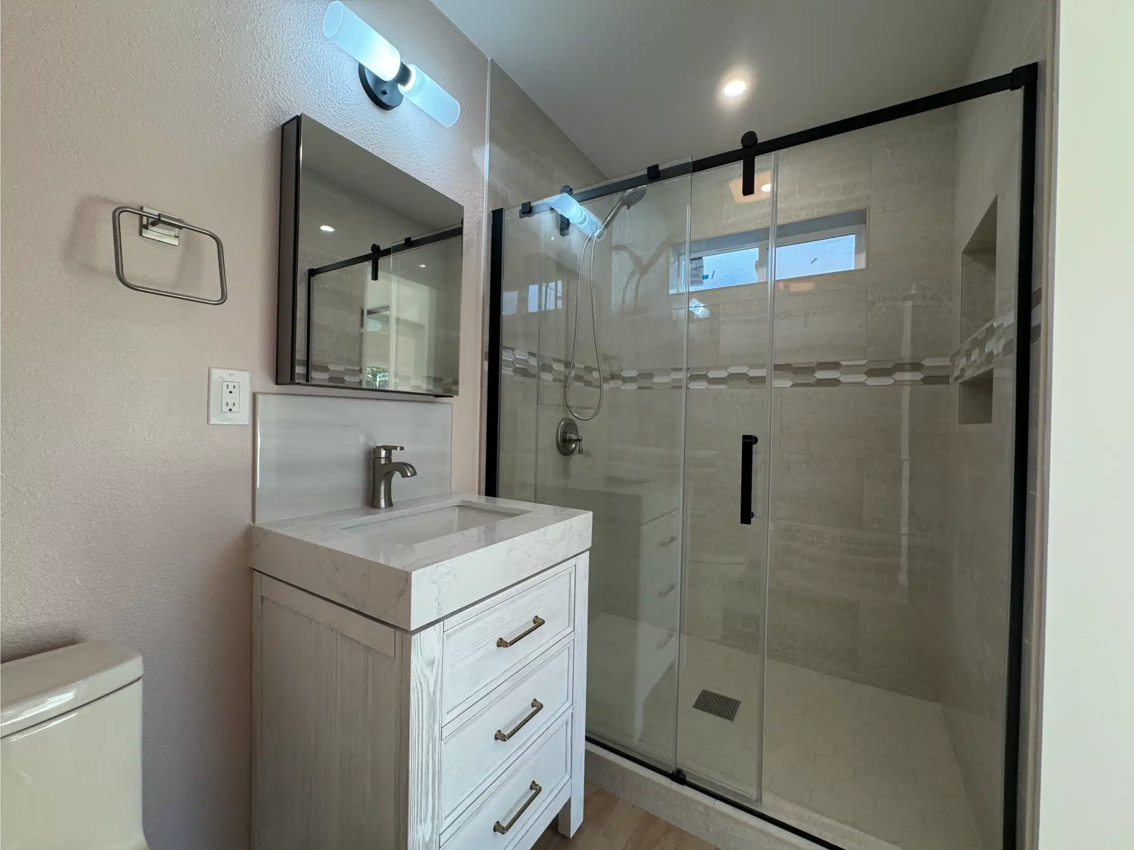 Completed ADU bathroom with a framed vanity and frameless glass shower