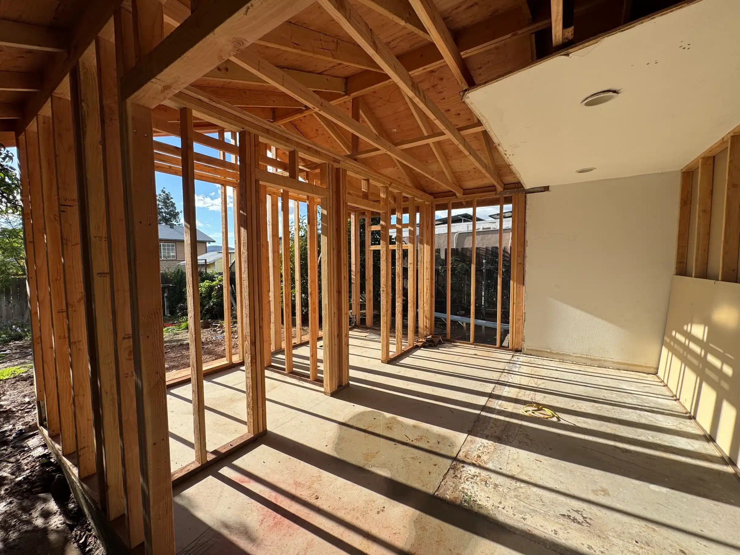 Open framing at the Santee addition with sunlight through the studs