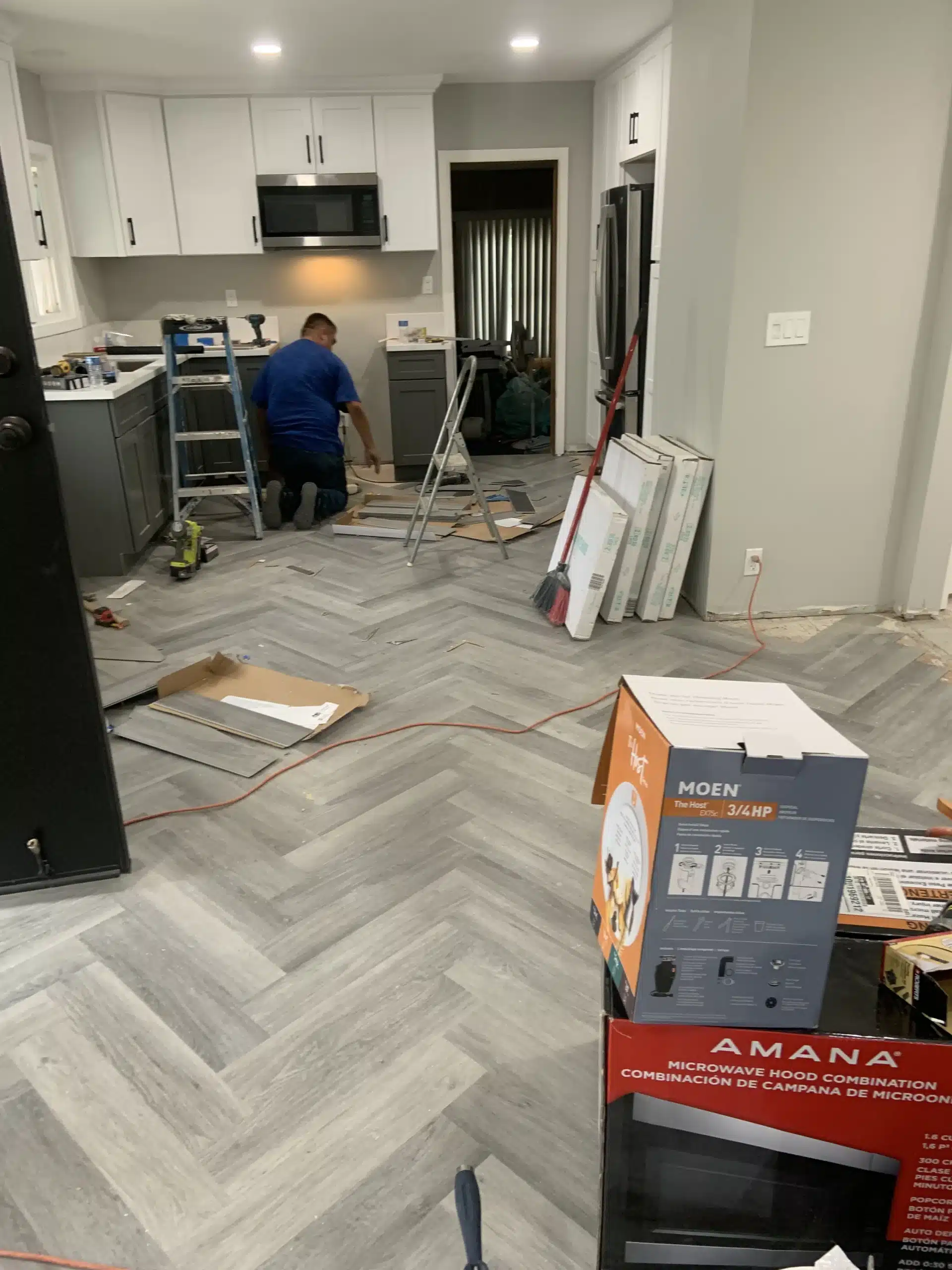 Cabinetry going in while the herringbone floor is part-laid and appliances are still boxed