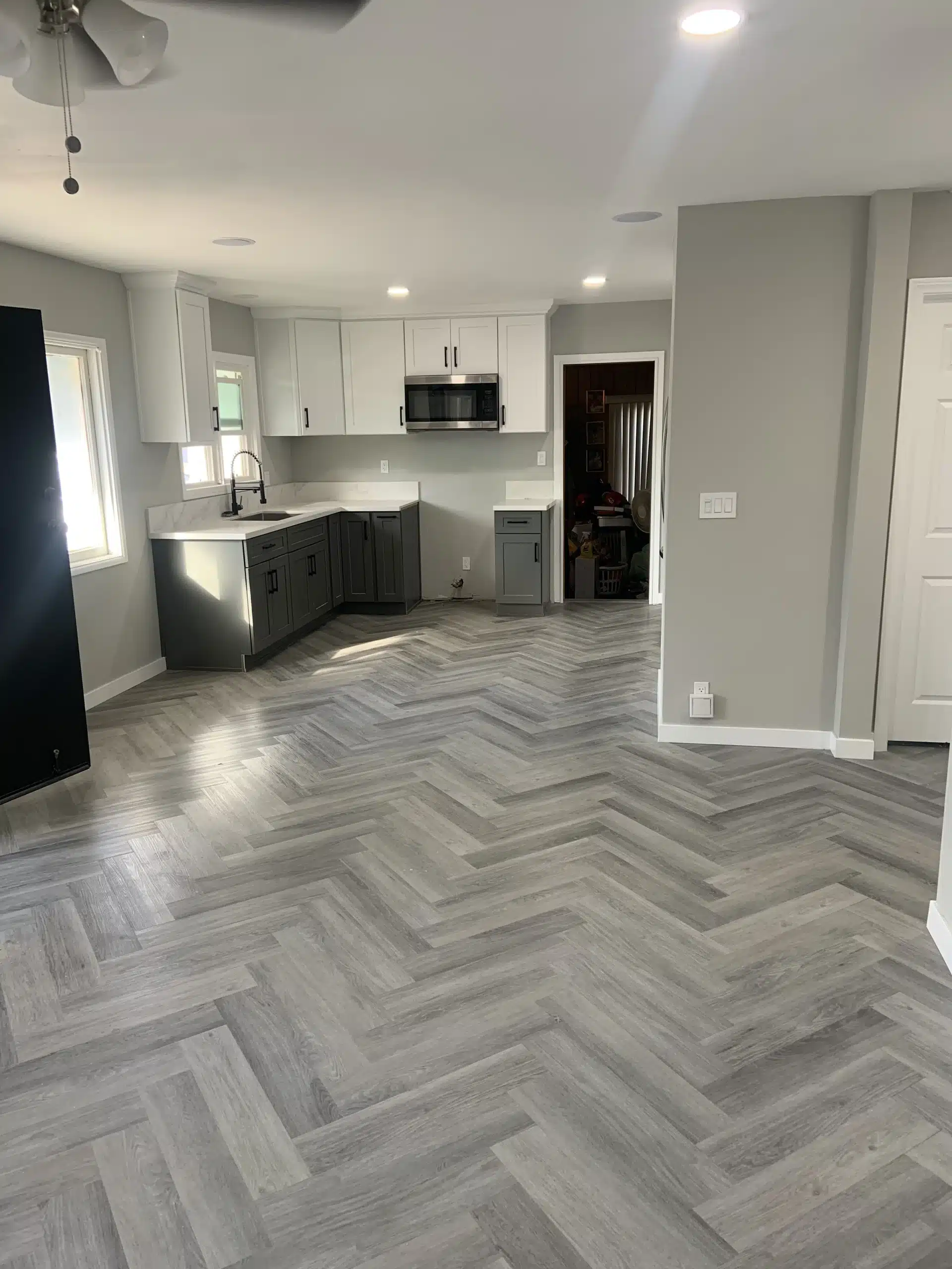 The same space after the remodel, with a kitchen island, two-tone cabinetry and herringbone flooring
