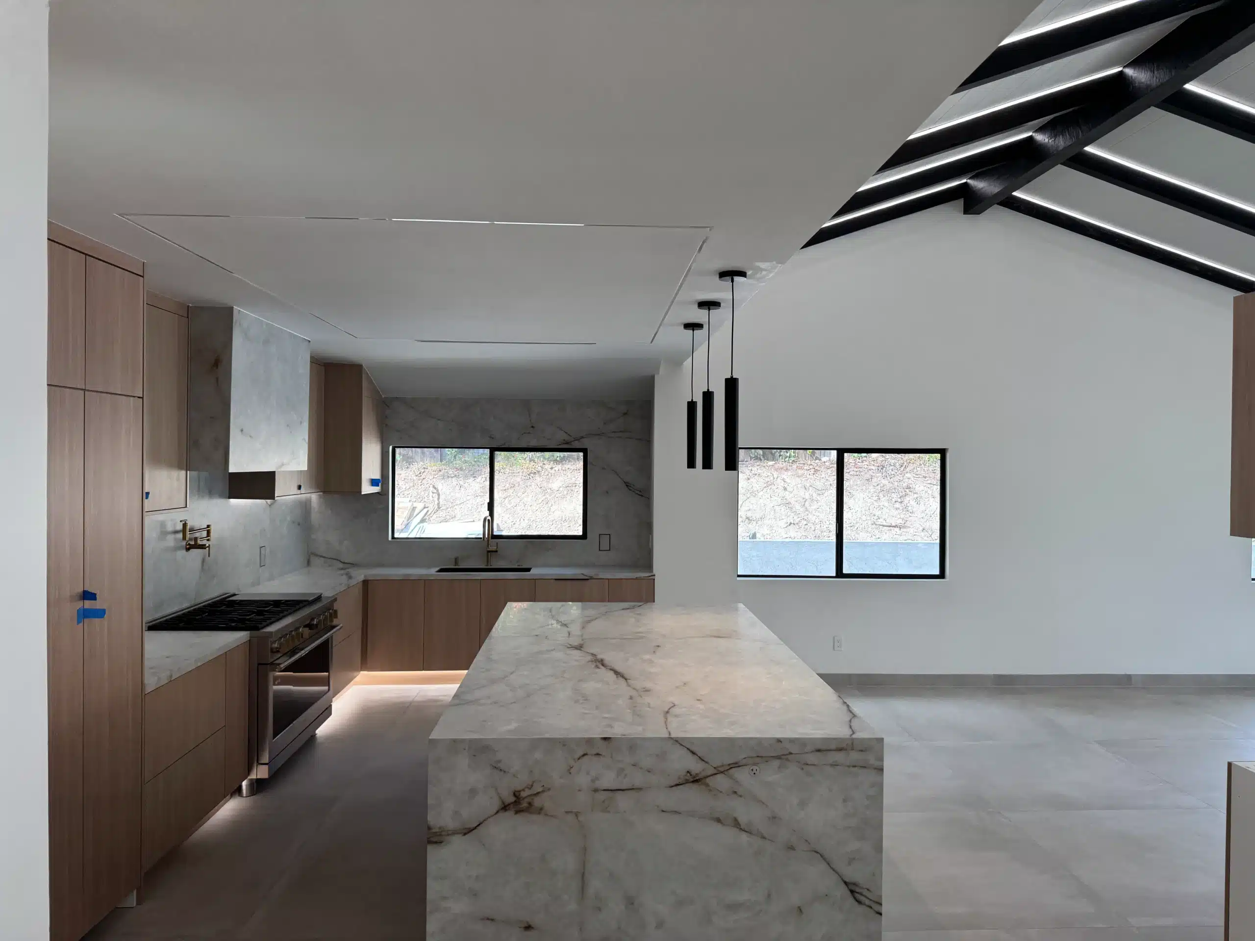 Relocated kitchen in Scripps Ranch with a veined marble waterfall island, full-height oak cabinetry and integrated under-cabinet lighting