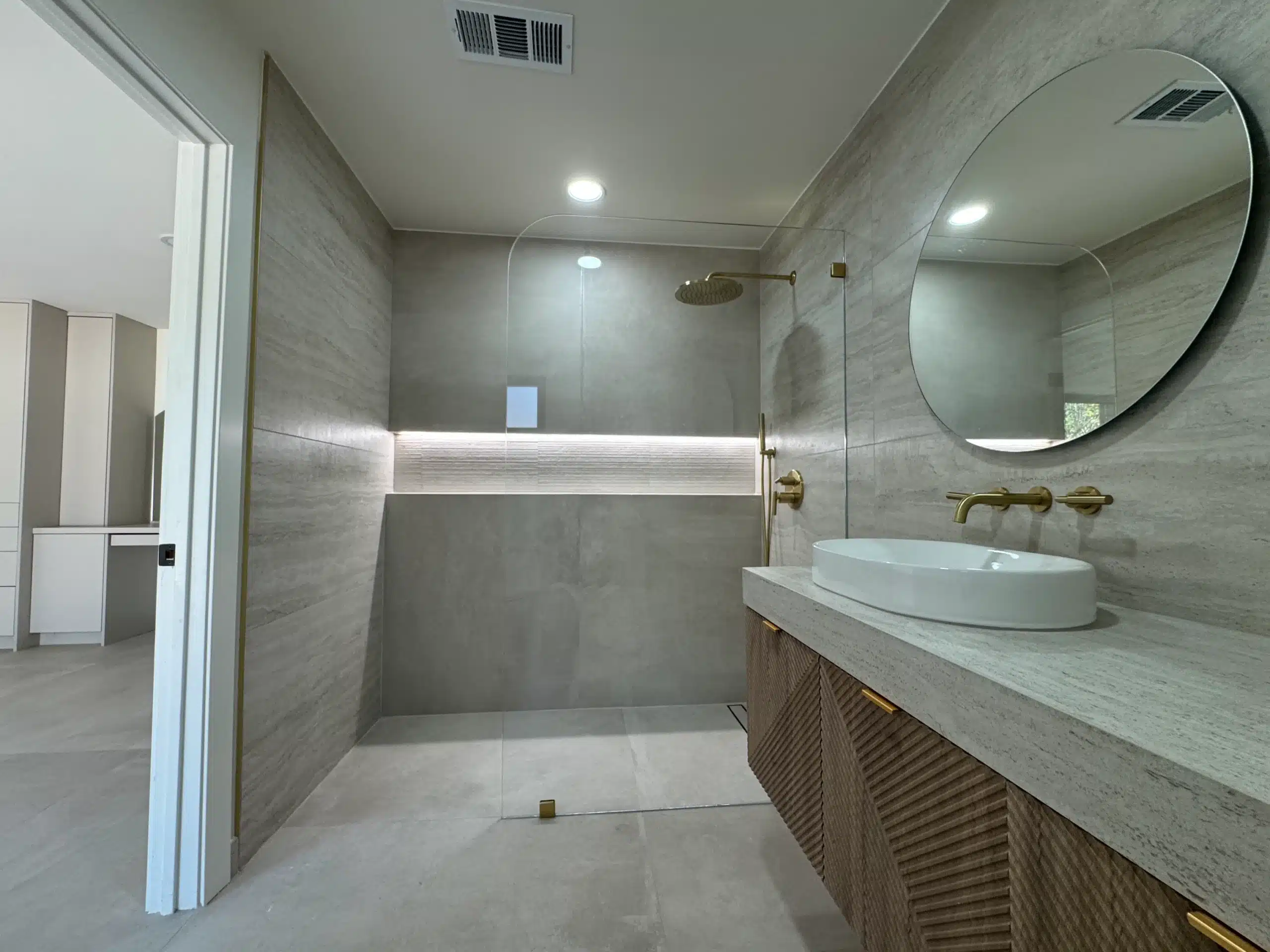 Bathroom vanity wall with brass tapware and a concealed LED strip beneath the mirror