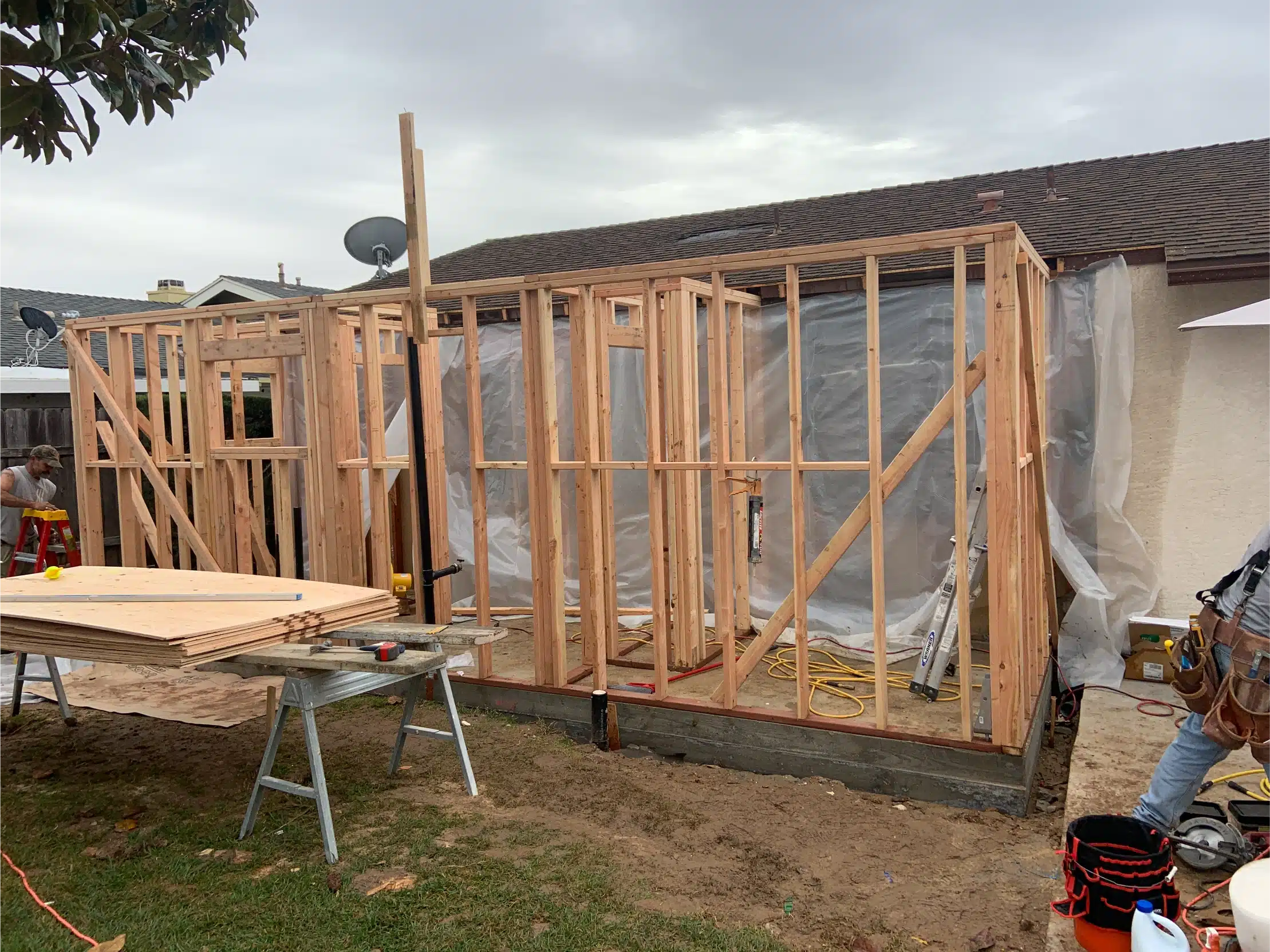 The addition framed out with studs and openings formed, wrapped against weather