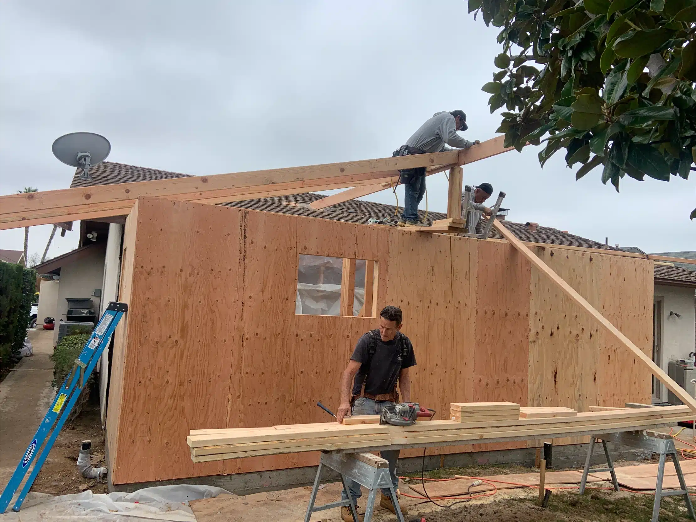 A framed wall being raised into position on the new footing