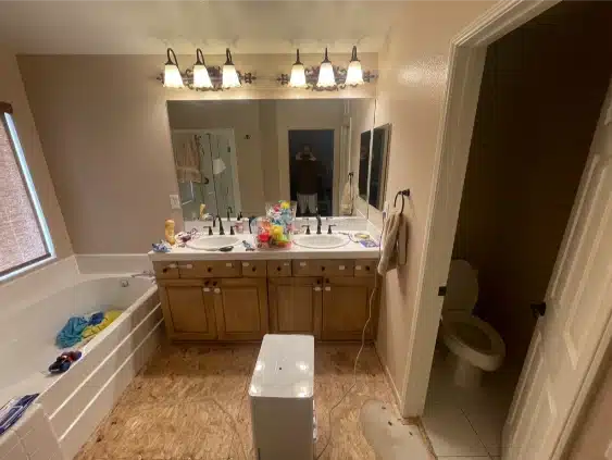 The bathroom before the remodel, with an oak vanity, tub-shower and dated tile