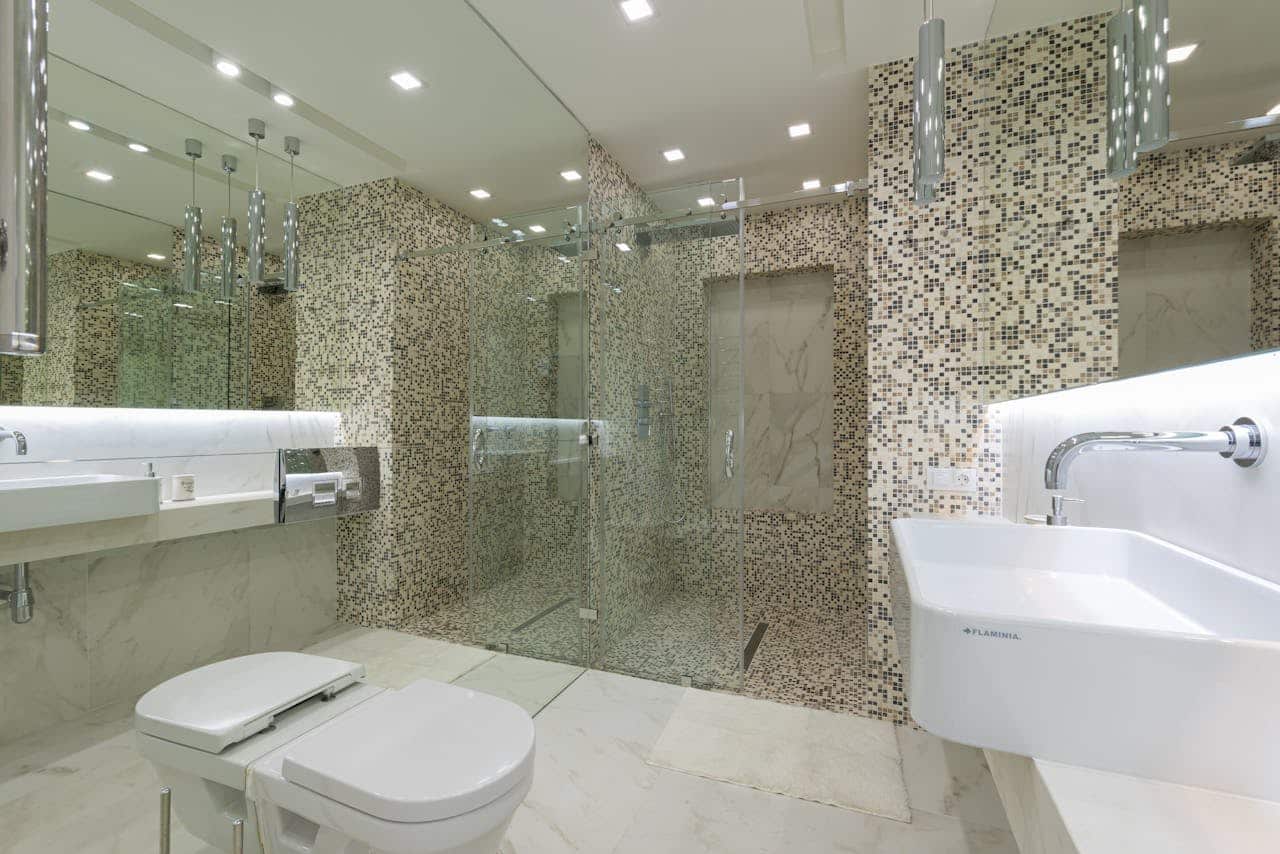 Walk-in shower with pebble mosaic tile, a frameless glass screen and a mirrored wall
