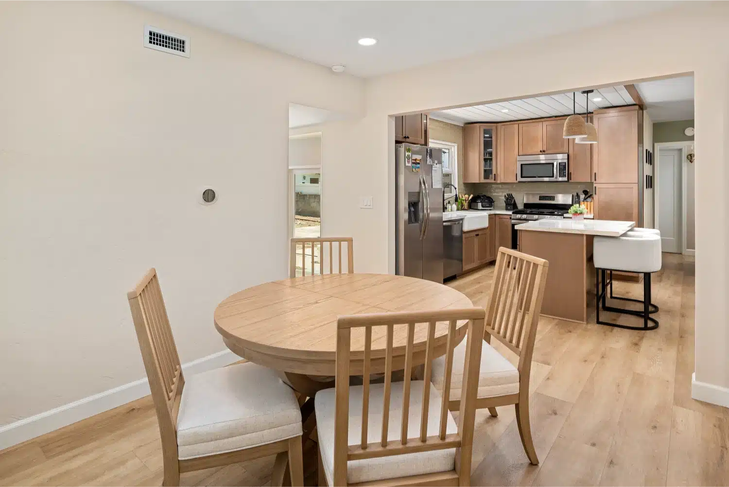 Whole-home remodel in San Diego County finished in warm oak, seen from the dining room into the kitchen