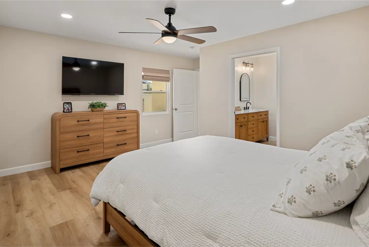 Bedroom seen toward the oak dresser and wall-mounted television