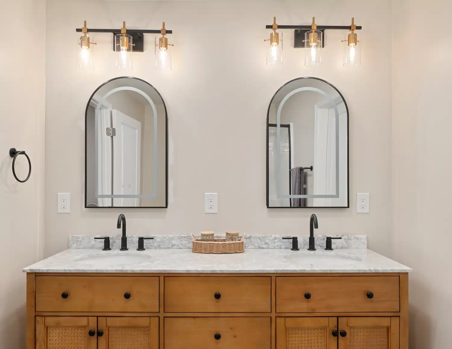 Close view of the double vanity showing the arched mirrors and matte black hardware