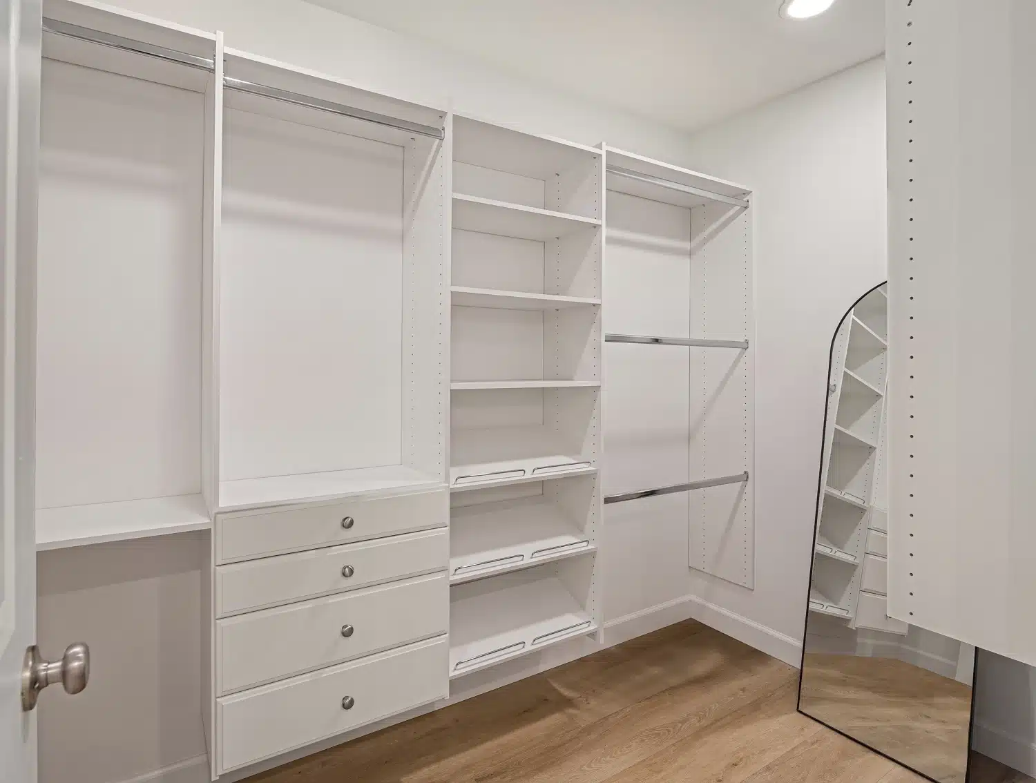 Fitted walk-in closet with white shelving, hanging rails and built-in drawers
