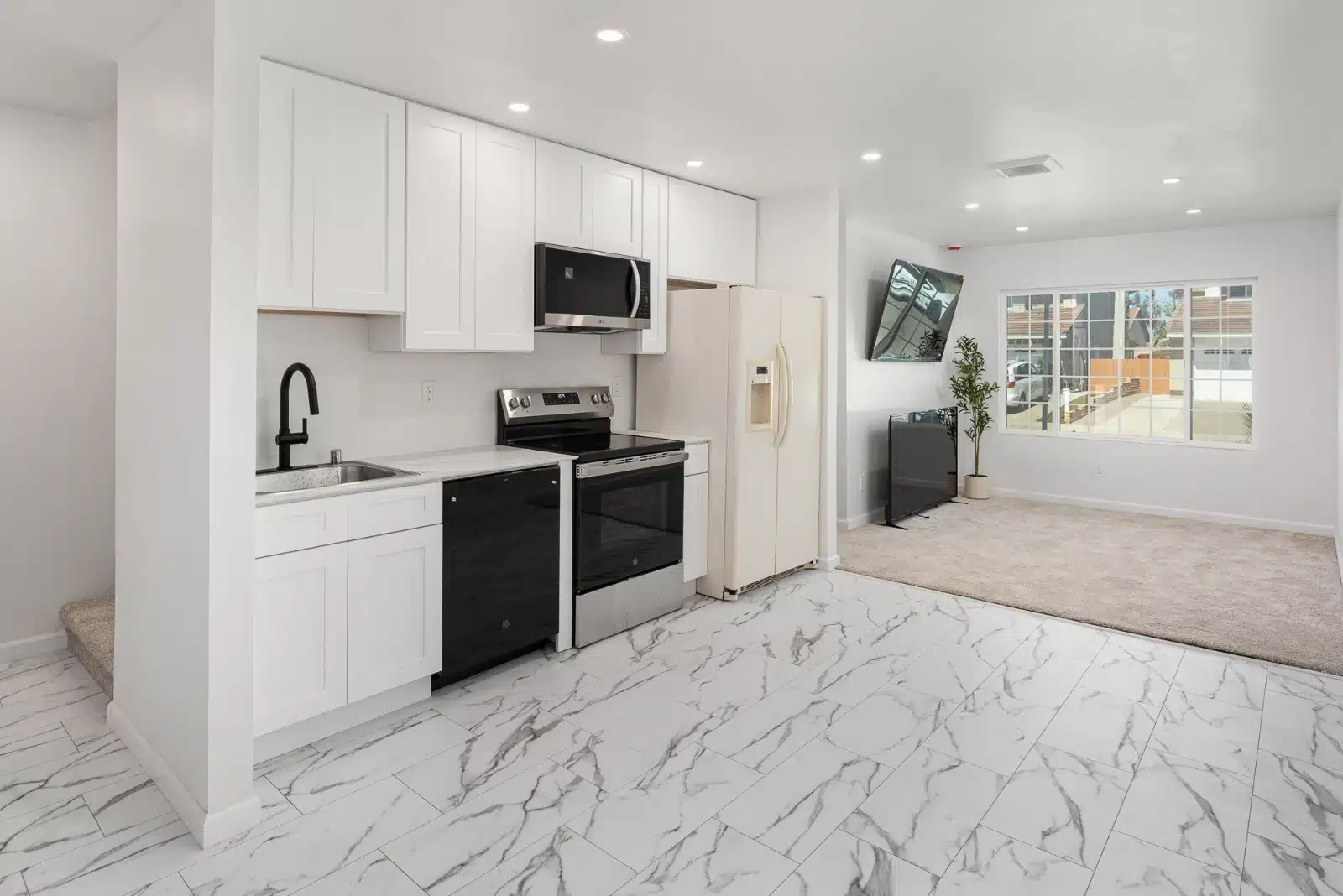 Kitchen and living area in the addition, with white cabinetry, a stainless range and a black dishwasher