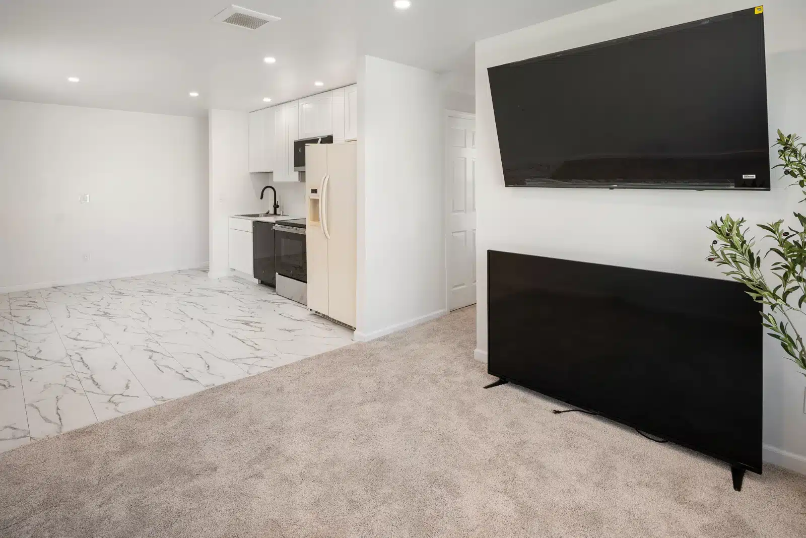 Living area opening into the kitchen, with carpet meeting the tiled kitchen floor