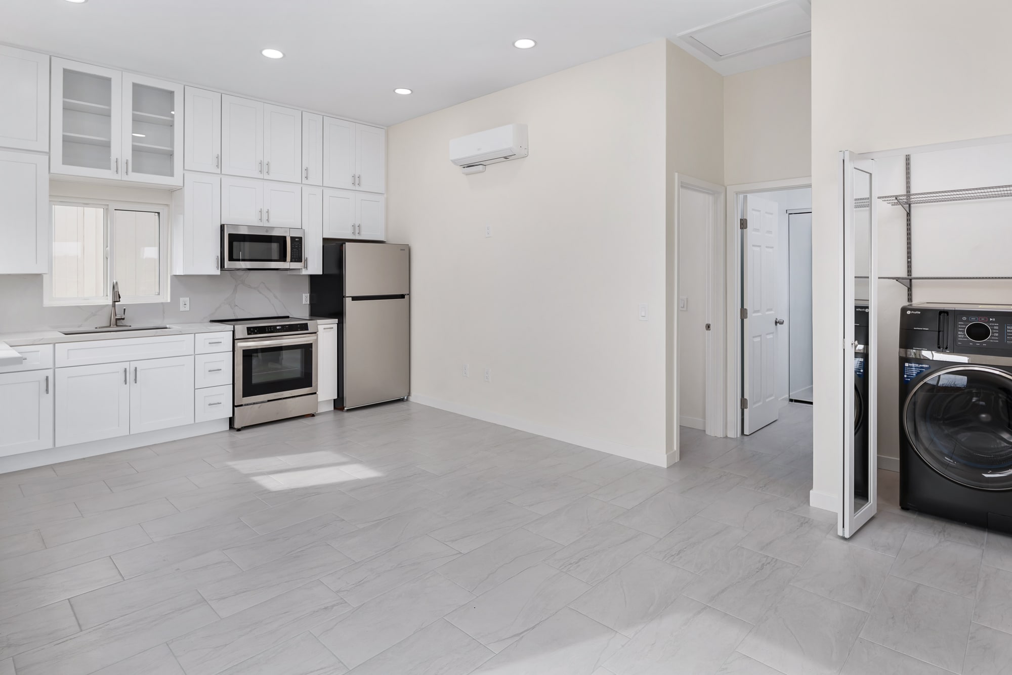 Finished ADU kitchen and living space with white shaker cabinets, stainless appliances and tile flooring