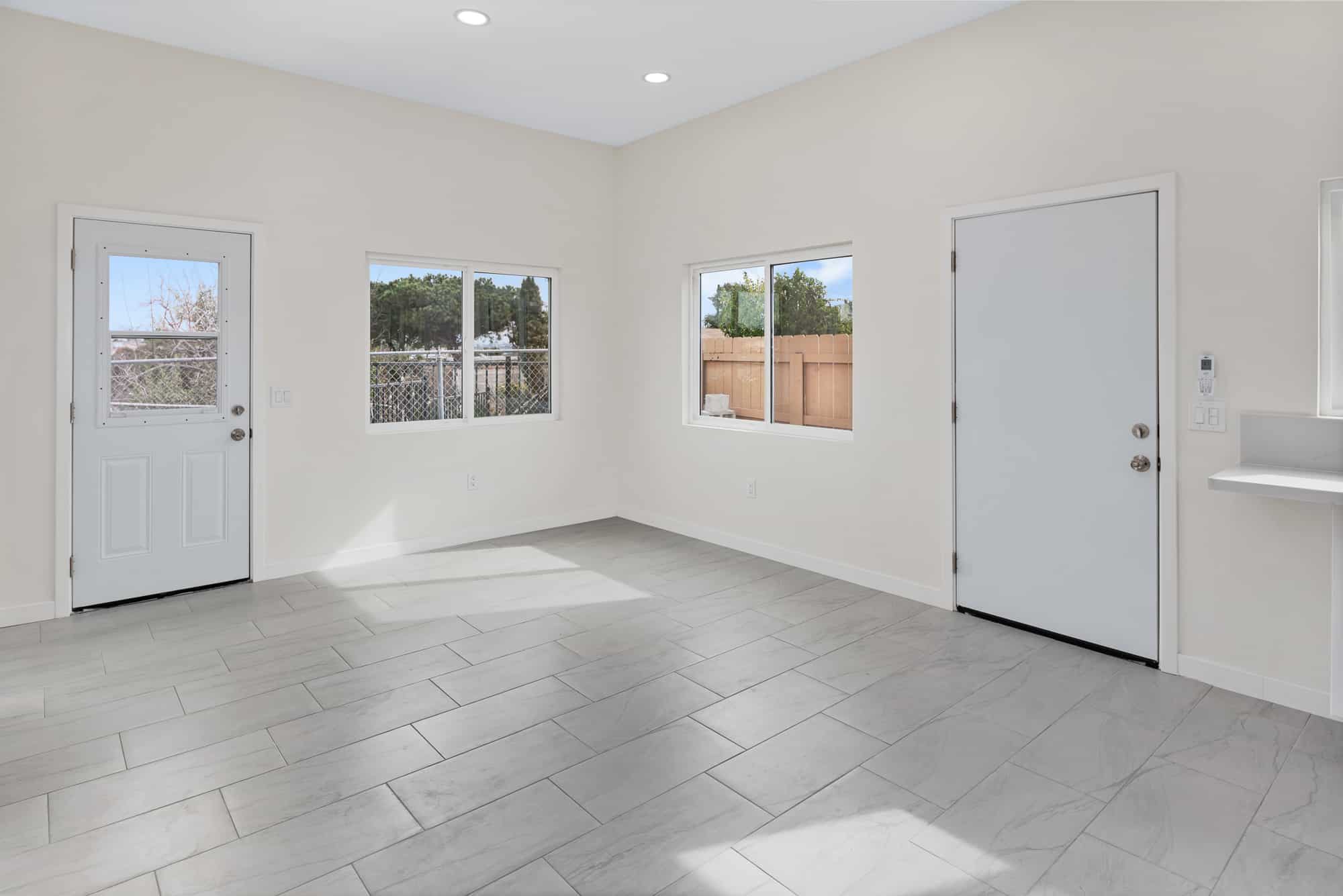 ADU living space with two exterior doors, windows on three sides and tile flooring