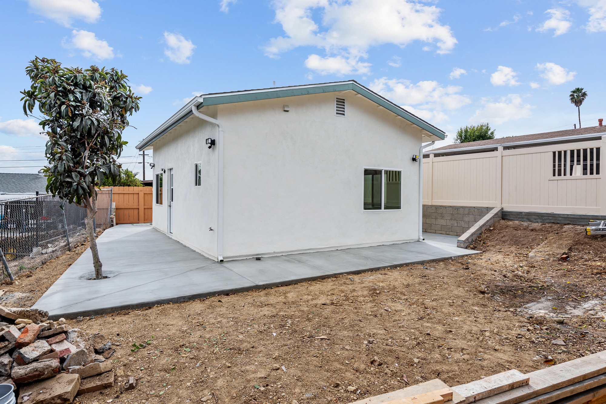 Side of the completed ADU with a new concrete path and the yard beyond