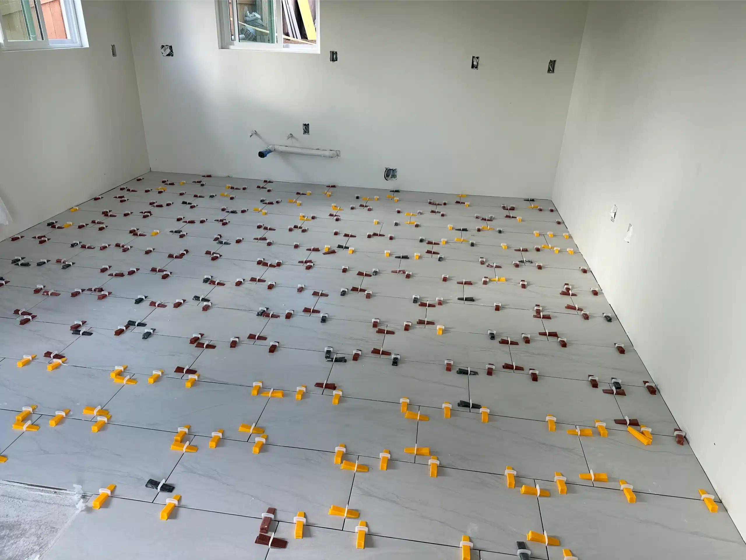 Large-format floor tile being laid in the ADU with a tile levelling system