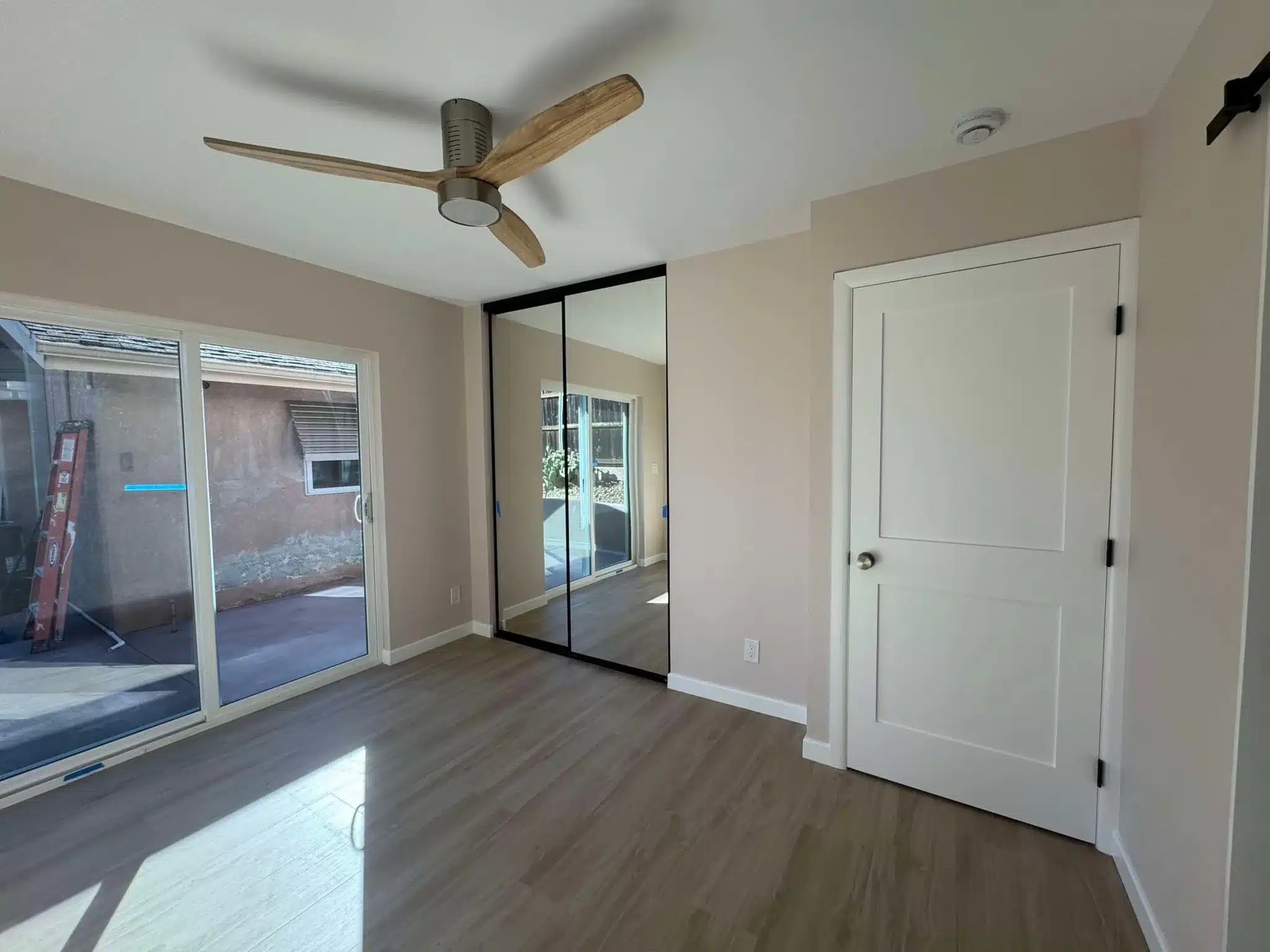 Bedroom with mirrored closet doors, ceiling fan, and glass sliding doors to patio